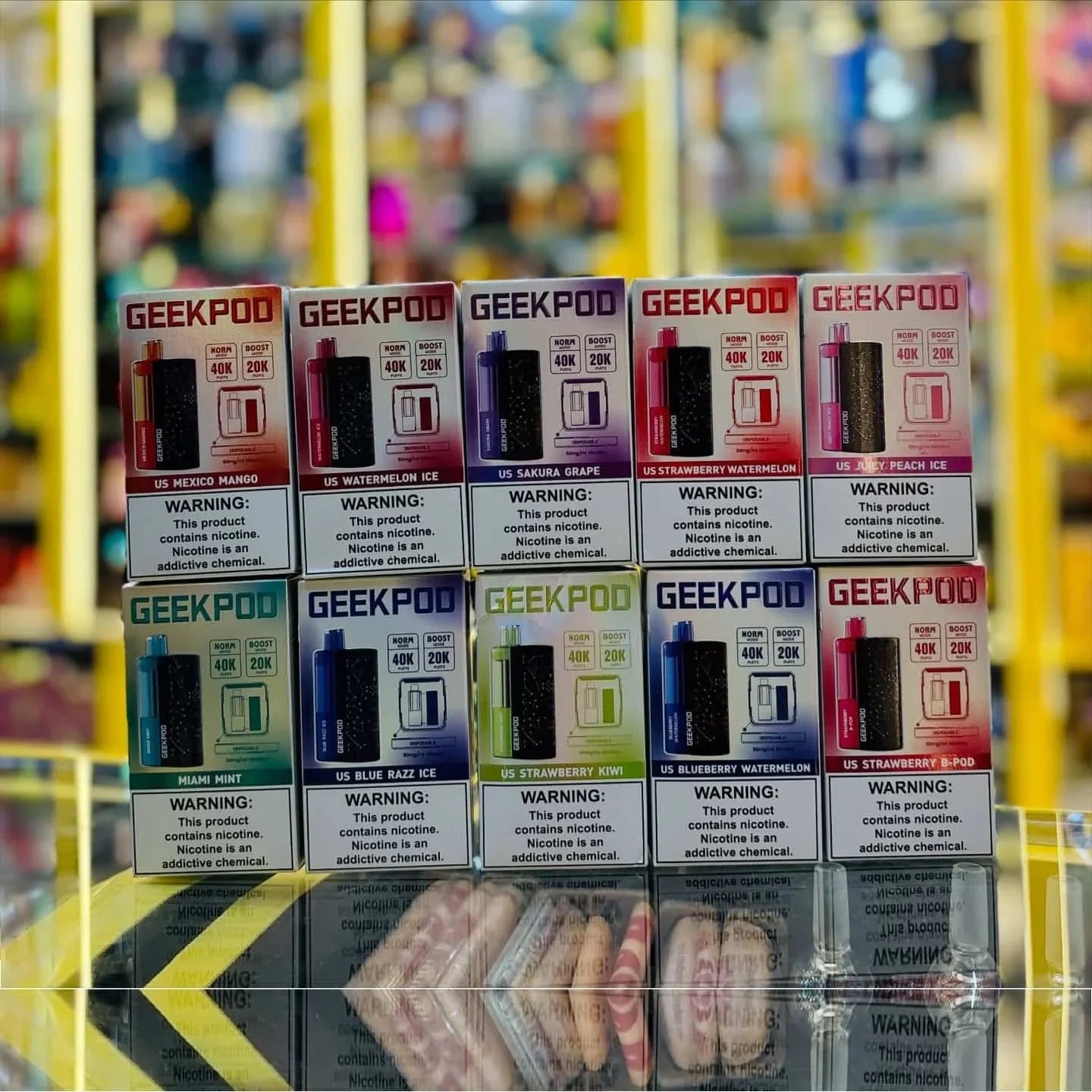 Stack of GeekPod vape device boxes with colorful packaging on a blurred background