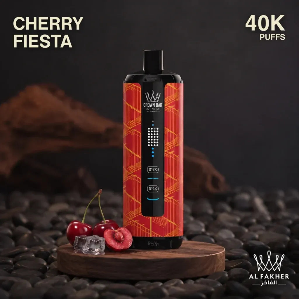 A Crown Bar disposable vape device in Cherry Fiеста flavor, featuring a red and orange geometric pattern with a black central control panel. The vape is displayed on a wooden block surrounded by fresh cherries and ice cubes, set against a dark background of pebbles and wood logs.