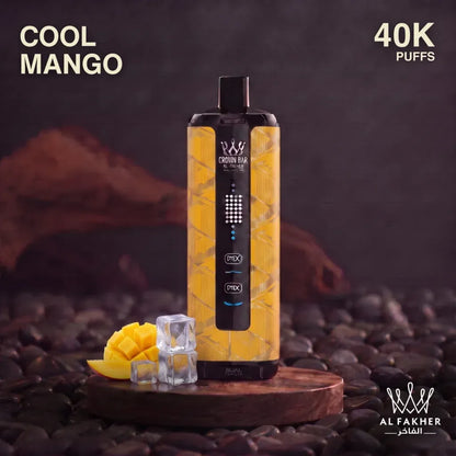 A al fakher crown bar disposable vape device labeled 'COOL MANGO' and '40K PUFFS' stands on a wooden tray over dark stones. The device has a yellow honeycomb-patterned body with a black top and bottom.